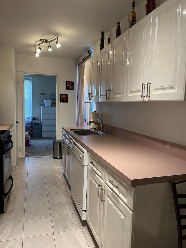 kitchen featuring black range oven, dishwashing machine, sink, light tile patterned floors, and white cabinetry