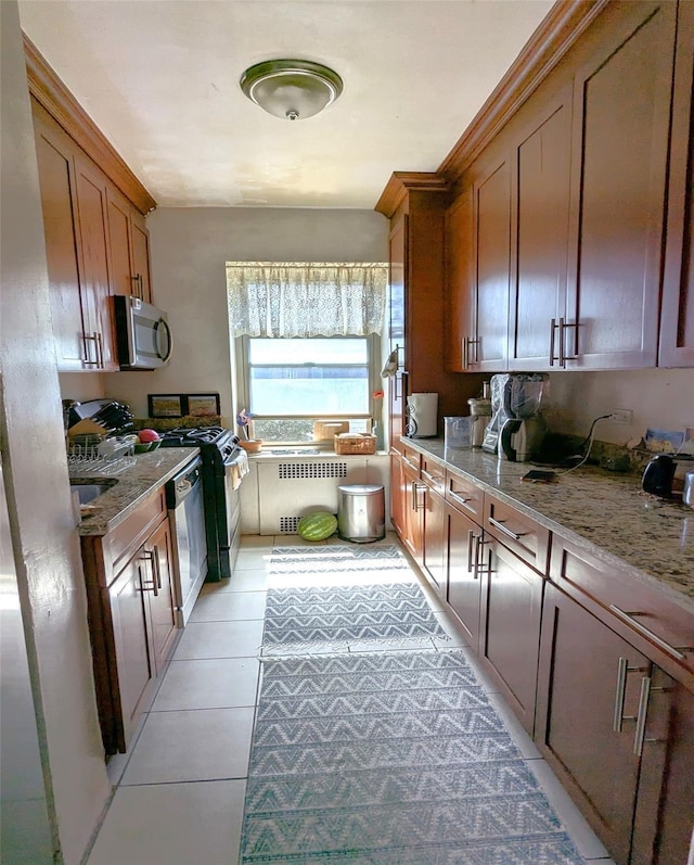 kitchen featuring radiator, light stone counters, light tile patterned flooring, and range with gas cooktop