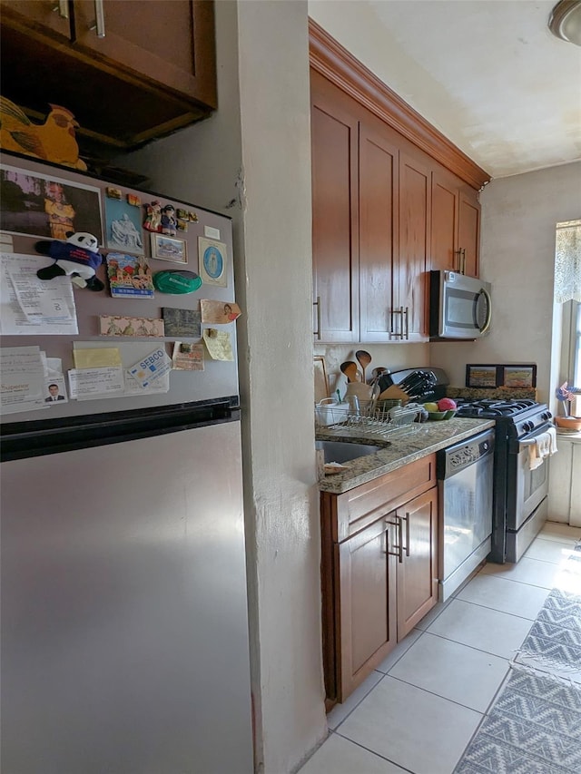 kitchen featuring light stone countertops, sink, light tile patterned flooring, and appliances with stainless steel finishes