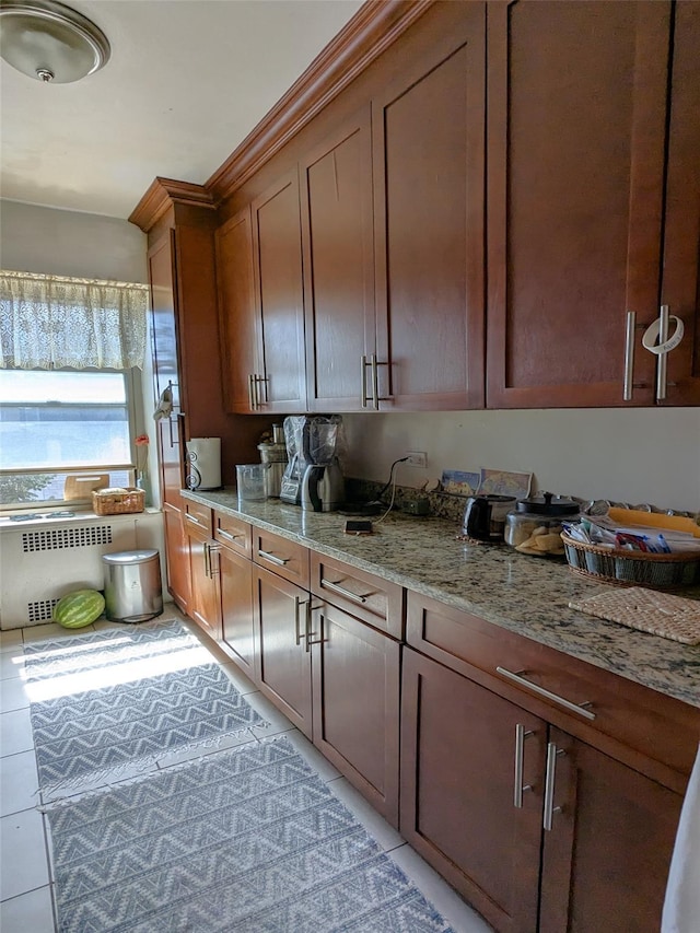 kitchen with light stone countertops, radiator heating unit, and light tile patterned floors