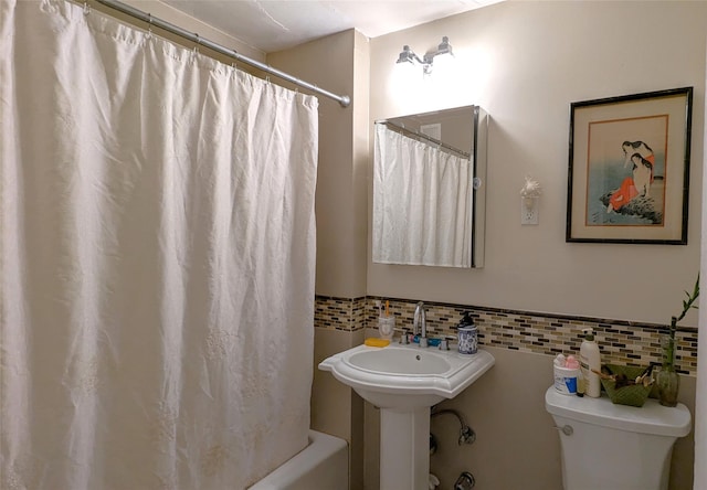 bathroom with shower / bath combination with curtain, toilet, and backsplash