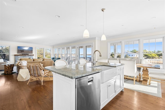 kitchen featuring white cabinetry, stainless steel dishwasher, stone countertops, decorative light fixtures, and a kitchen island with sink