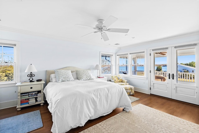 bedroom featuring dark wood-type flooring, access to outside, a water view, ceiling fan, and multiple windows