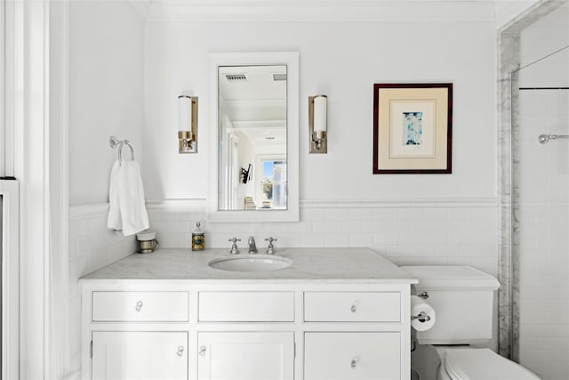 bathroom with walk in shower, crown molding, toilet, vanity, and tile walls