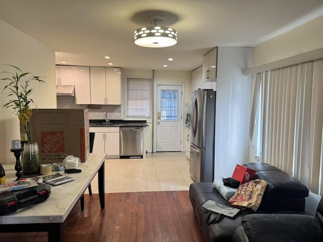 kitchen with light hardwood / wood-style flooring, stainless steel appliances, tasteful backsplash, white cabinetry, and sink