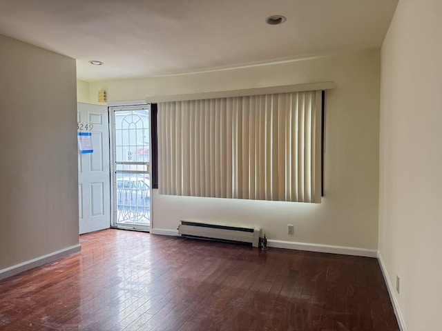 unfurnished room with a baseboard radiator and dark hardwood / wood-style floors