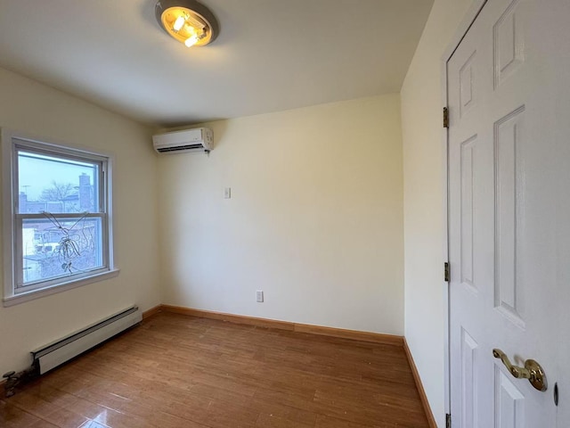 unfurnished room with baseboard heating, a wall mounted AC, and hardwood / wood-style floors