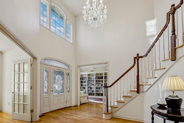 entrance foyer with a high ceiling, hardwood / wood-style flooring, and a notable chandelier