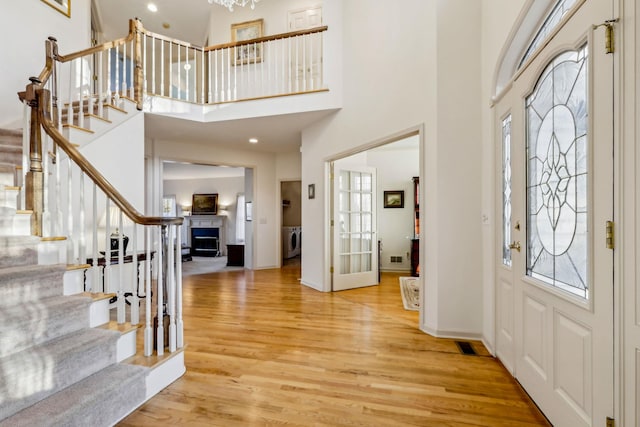 entrance foyer with a towering ceiling, washer / dryer, and light hardwood / wood-style flooring