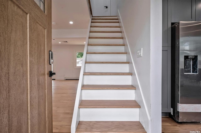 stairway with wood-type flooring and baseboard heating