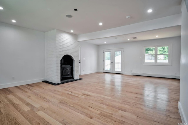 unfurnished living room featuring french doors, light wood-type flooring, a baseboard radiator, and a wood stove