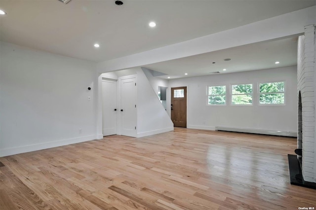 unfurnished living room featuring light hardwood / wood-style floors and a baseboard heating unit