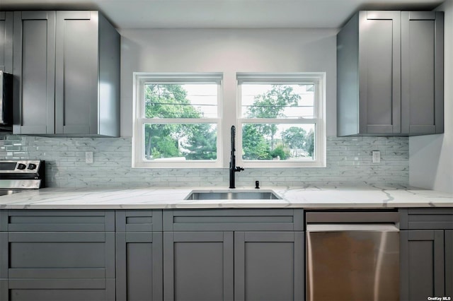 kitchen featuring stainless steel dishwasher, gray cabinets, and sink