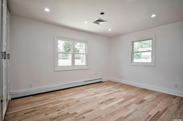 unfurnished room with baseboard heating and light hardwood / wood-style flooring