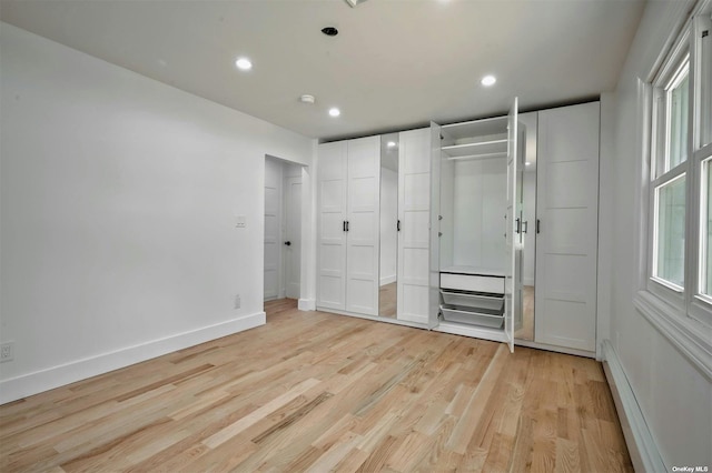 unfurnished bedroom with light wood-type flooring and baseboard heating