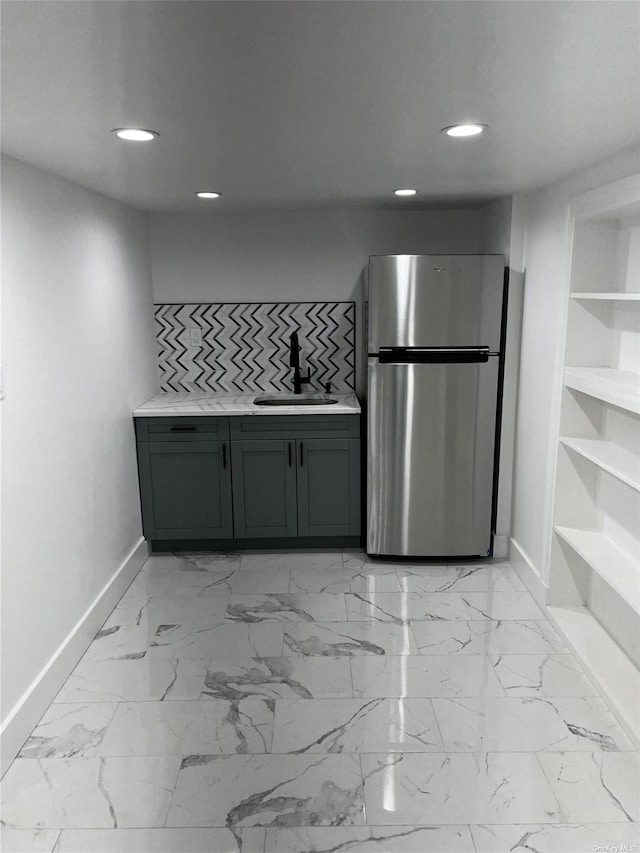 kitchen with gray cabinetry, stainless steel fridge, and sink