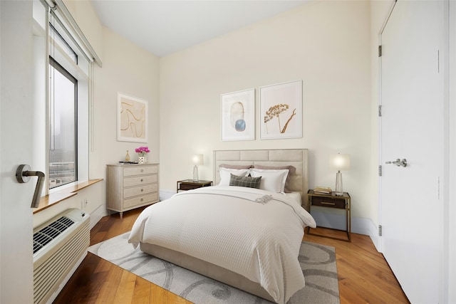 bedroom with wood-type flooring and an AC wall unit