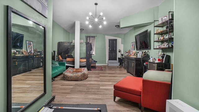 exercise area featuring light wood-type flooring, an inviting chandelier, and vaulted ceiling