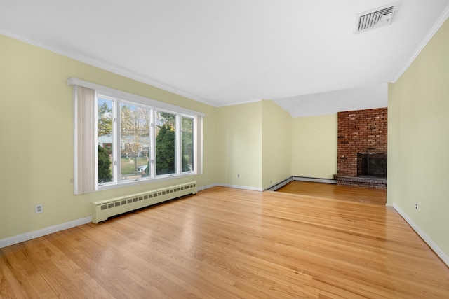 unfurnished living room featuring light wood-type flooring, baseboard heating, ornamental molding, and a brick fireplace