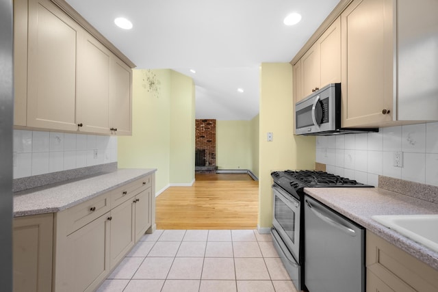 kitchen featuring a fireplace, light tile patterned floors, appliances with stainless steel finishes, and tasteful backsplash