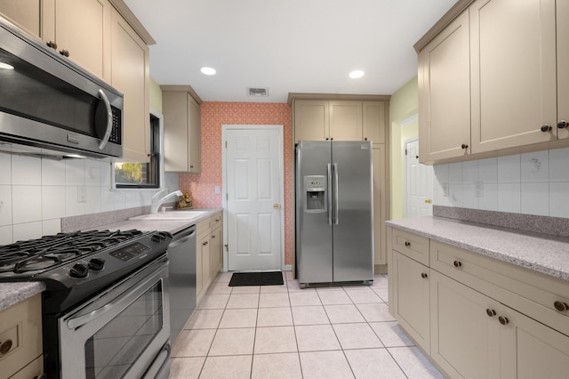 kitchen featuring decorative backsplash, appliances with stainless steel finishes, sink, and light tile patterned flooring