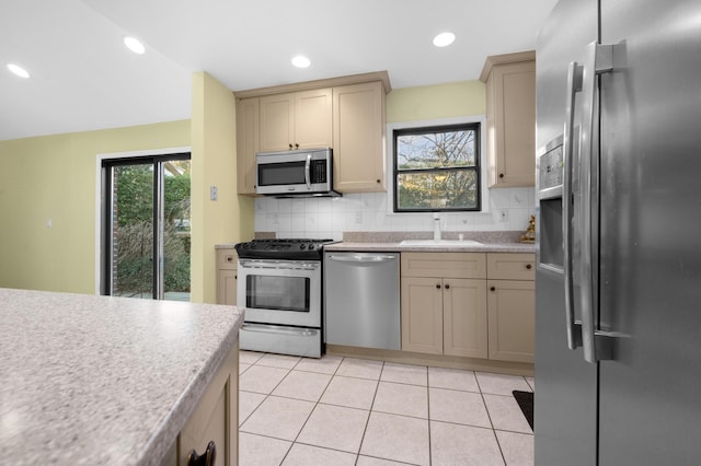 kitchen with light tile patterned floors, stainless steel appliances, tasteful backsplash, and sink