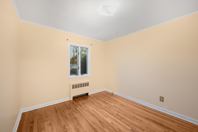 empty room featuring radiator, ornamental molding, and light hardwood / wood-style flooring