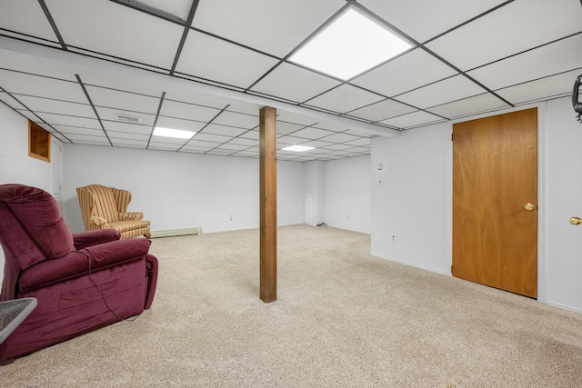 basement featuring a paneled ceiling, light colored carpet, and a baseboard radiator