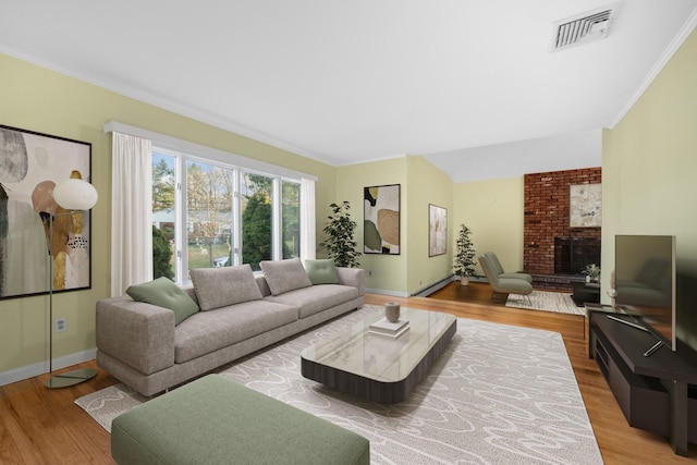 living room featuring a fireplace, crown molding, and light hardwood / wood-style flooring