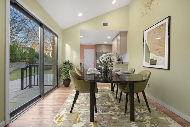 dining area featuring lofted ceiling and light wood-type flooring