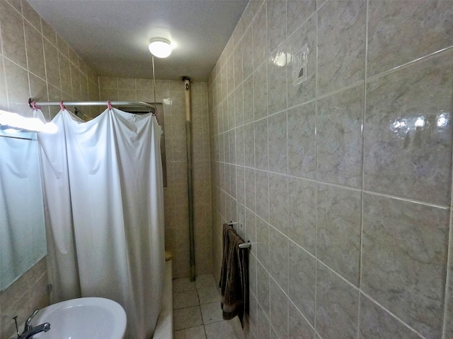 bathroom featuring tile patterned floors, curtained shower, sink, and tile walls