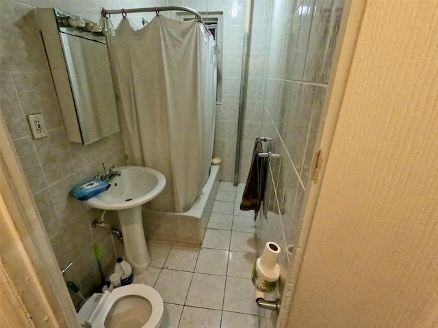 bathroom featuring tile patterned floors, toilet, and tile walls