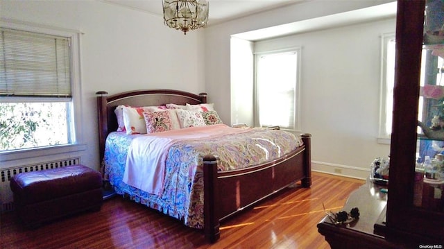 bedroom featuring a notable chandelier, wood-type flooring, and radiator