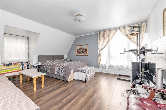 bedroom with wood-type flooring, multiple windows, and lofted ceiling