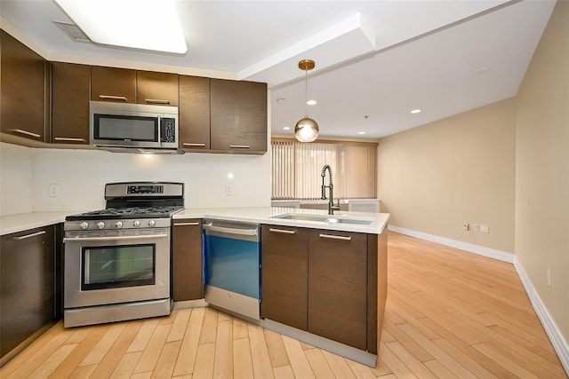 kitchen featuring dark brown cabinetry, sink, stainless steel appliances, kitchen peninsula, and pendant lighting