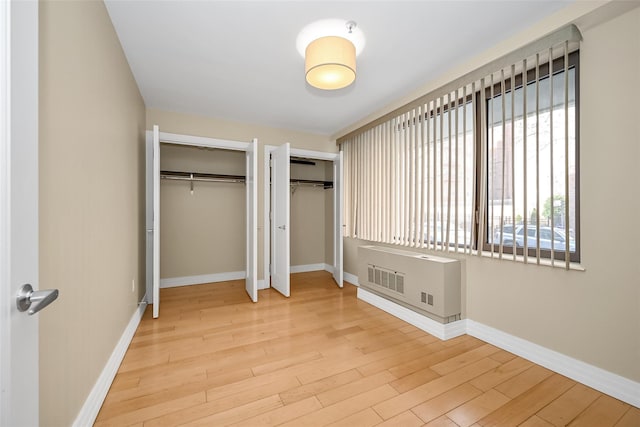 unfurnished bedroom with hardwood / wood-style floors and two closets