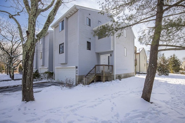 snow covered house featuring a garage