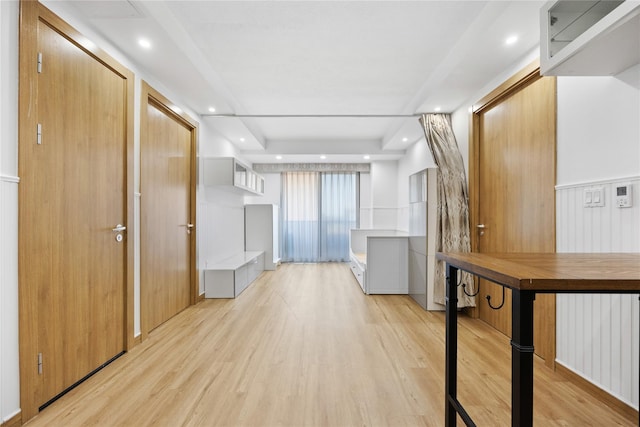 corridor with a raised ceiling and light hardwood / wood-style flooring