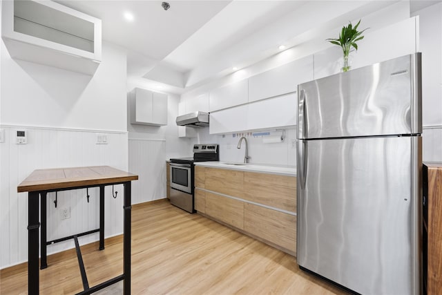 kitchen with exhaust hood, white cabinets, sink, light hardwood / wood-style floors, and stainless steel appliances