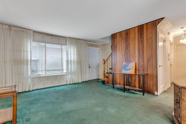 unfurnished room featuring dark colored carpet, a notable chandelier, and wood walls