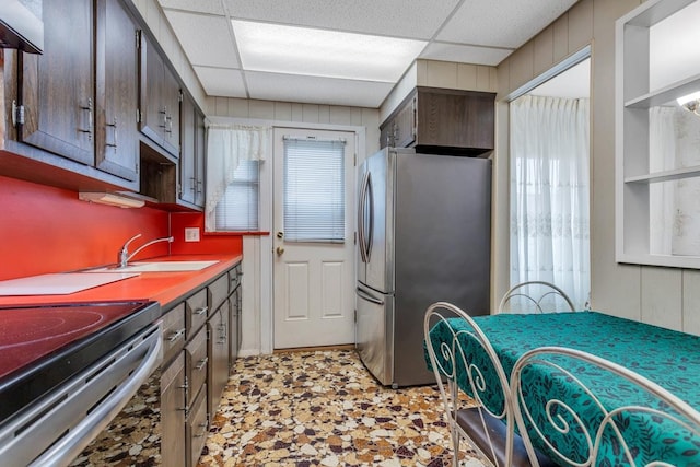 kitchen featuring a drop ceiling, range with electric cooktop, sink, and stainless steel refrigerator