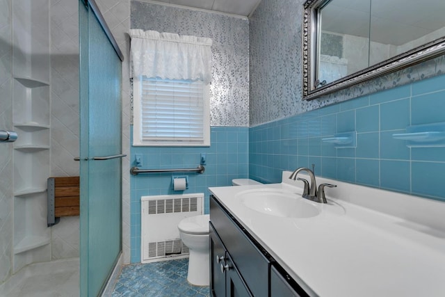 bathroom featuring radiator heating unit, toilet, vanity, a shower with shower door, and tile walls