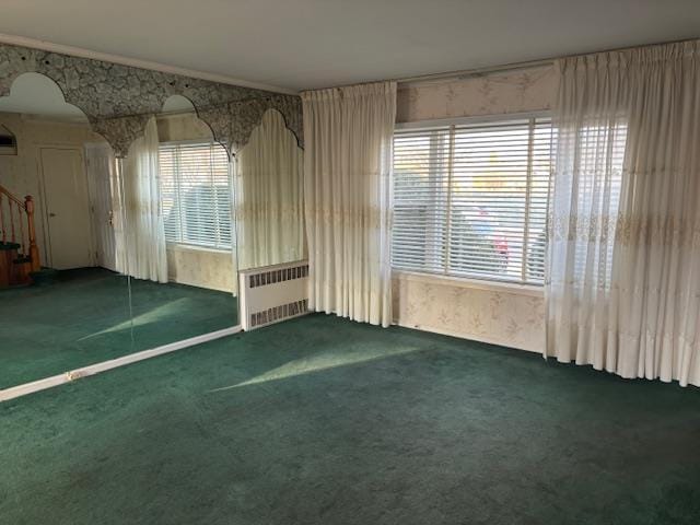 carpeted spare room with crown molding and radiator heating unit