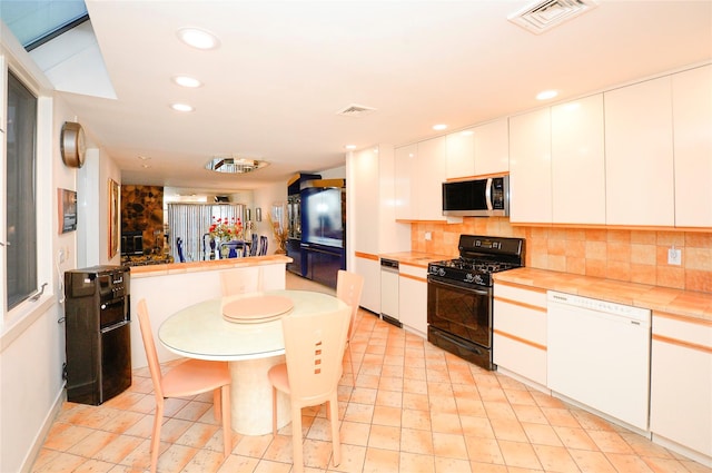 kitchen with black gas range, white cabinets, decorative backsplash, and white dishwasher