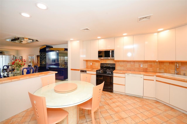 kitchen featuring black gas range, dishwasher, sink, backsplash, and white cabinets