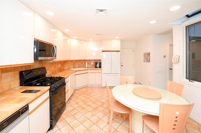 kitchen featuring sink, light tile patterned flooring, backsplash, white appliances, and white cabinets