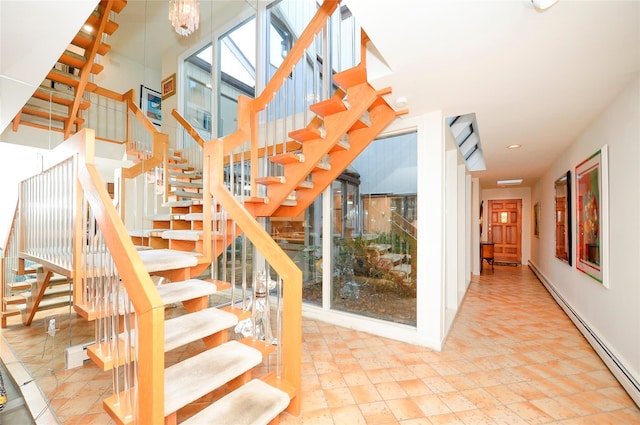 stairs with baseboard heating and an inviting chandelier