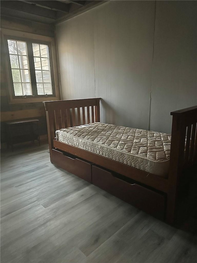 bedroom with hardwood / wood-style floors and wood walls