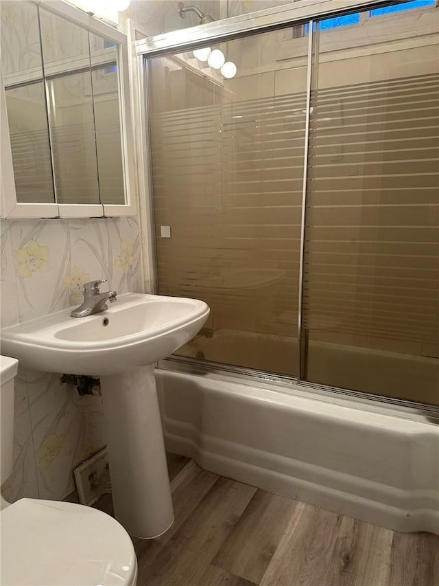 bathroom with hardwood / wood-style floors, toilet, enclosed tub / shower combo, and tasteful backsplash