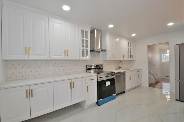 kitchen featuring sink, appliances with stainless steel finishes, wall chimney range hood, and white cabinetry